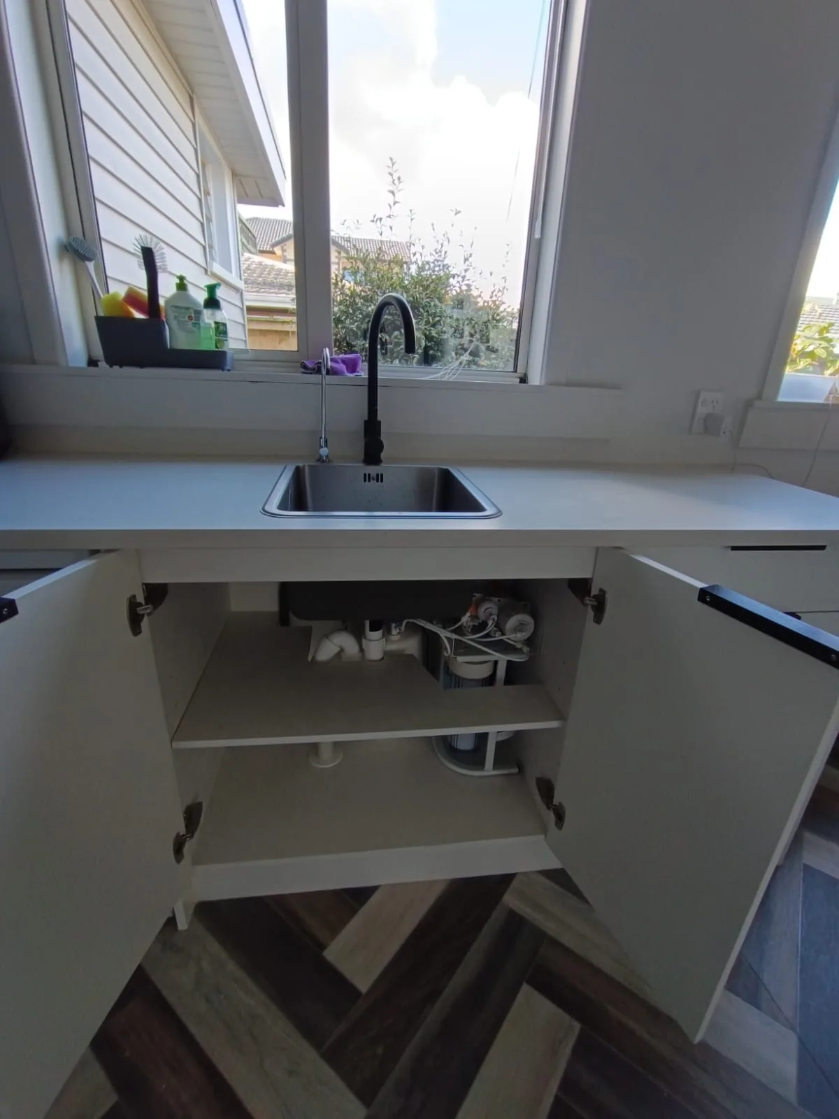 Under bench water filter installed beneath a kitchen sink with filtered water tap